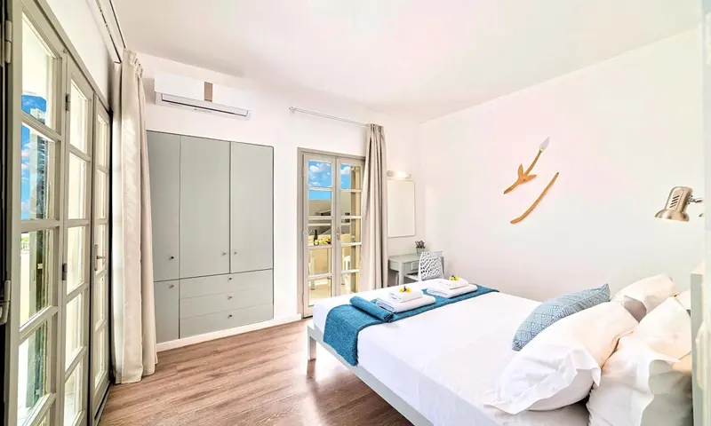 Une chambre lumineuse avec un lit fait et un accès à un balcon.
