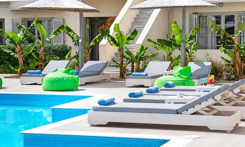 Transats et coussins colorés au bord d'une piscine ensoleillée.