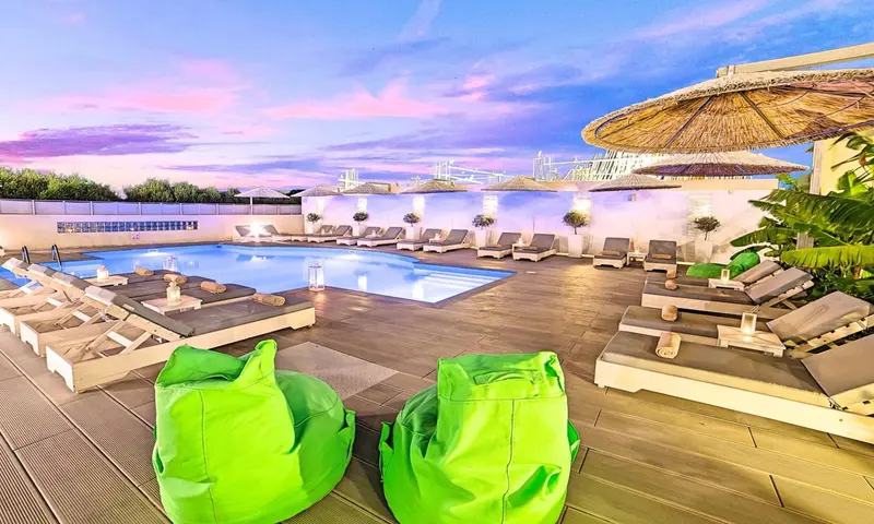 Terrasse avec piscine et chaises longues au coucher du soleil.