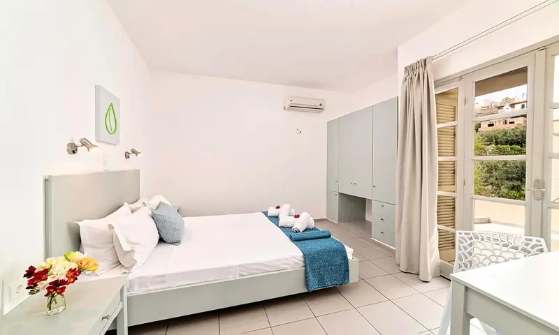Une chambre lumineuse avec un lit fait et un accès à une terrasse.