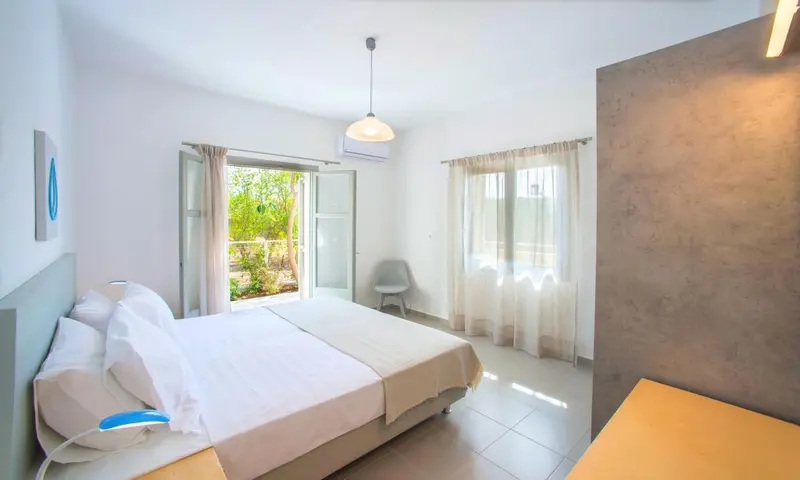 Une chambre lumineuse avec un grand lit et une vue sur la végétation.