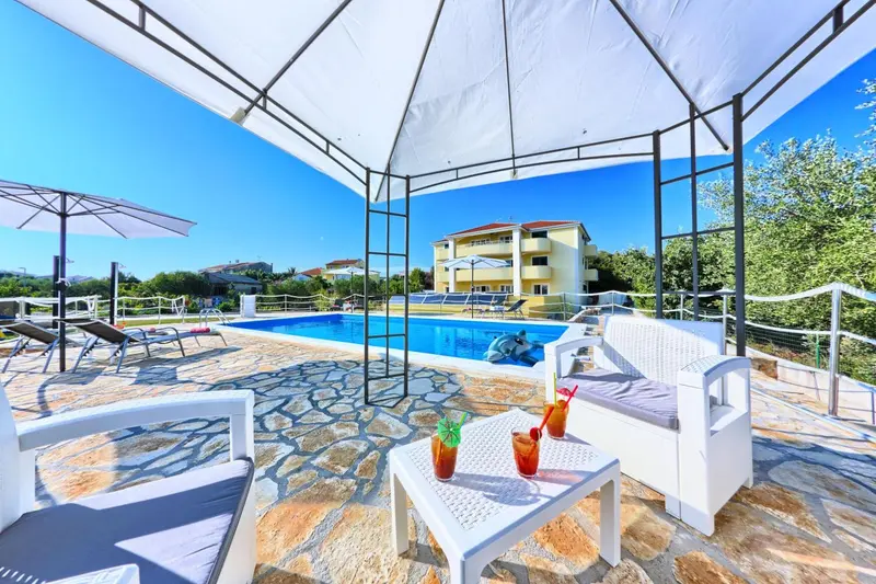 Terrasse aménagée avec des fauteuils blancs et une piscine en arrière-plan.