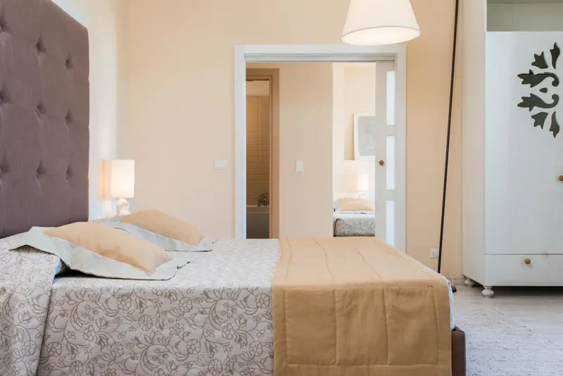 Une chambre lumineuse avec un grand lit et un accès à un autre espace.