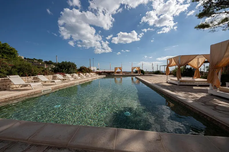 Une piscine rectangulaire bordée de chaises longues et de parasols.