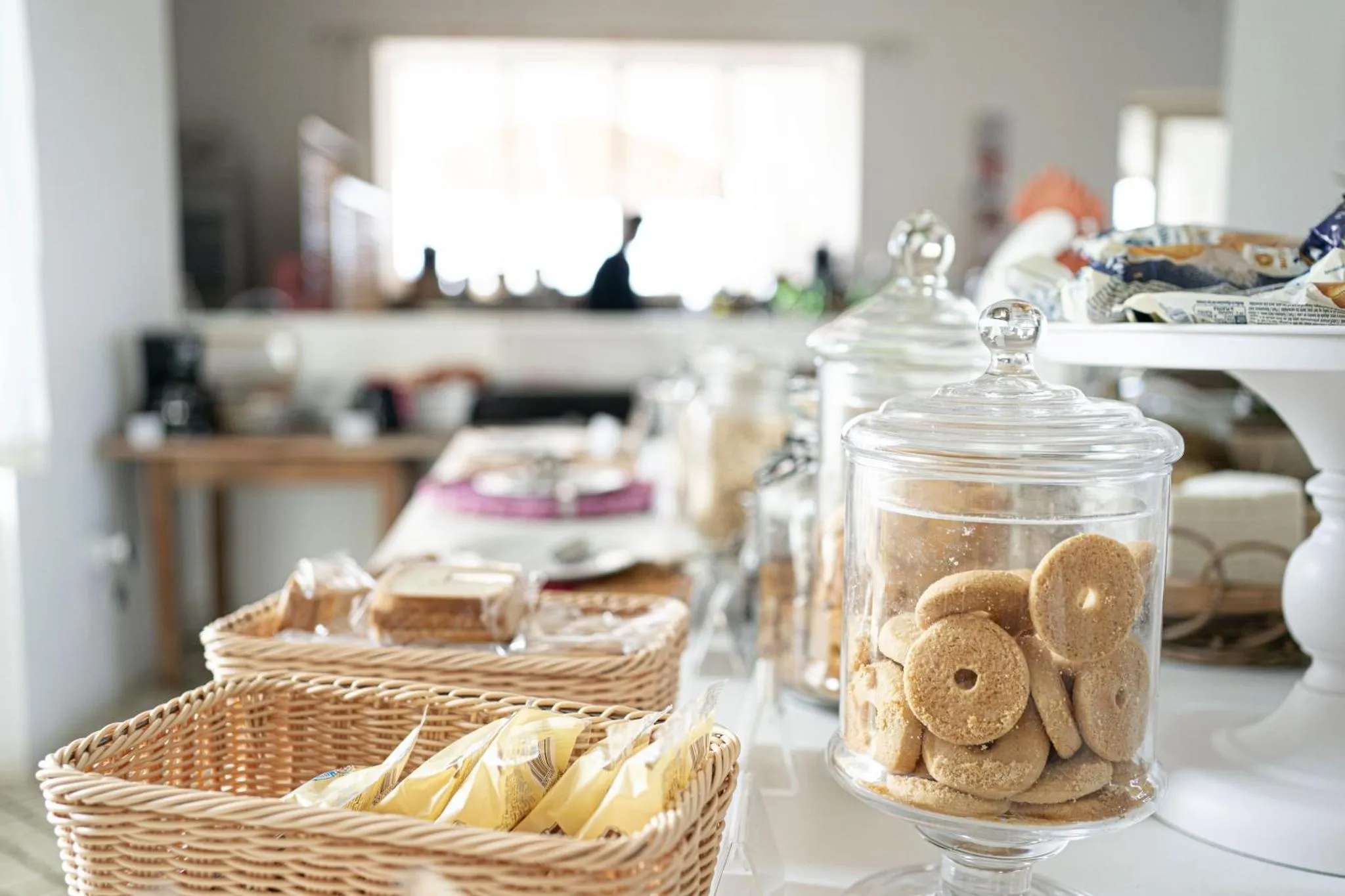 Un buffet propose des viennoiseries et des biscuits dans des récipients en verre.