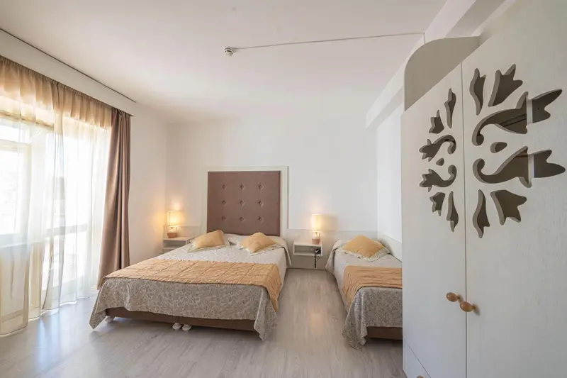 Une chambre lumineuse avec deux lits simples et un grand lit double.