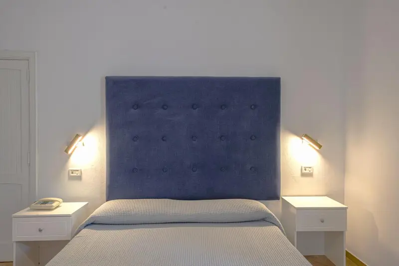 Une chambre lumineuse avec un grand lit recouvert d'une couette blanche.