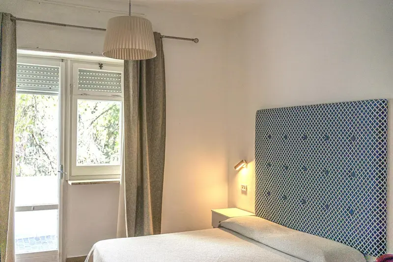 Une chambre lumineuse avec un lit et un accès à une terrasse.