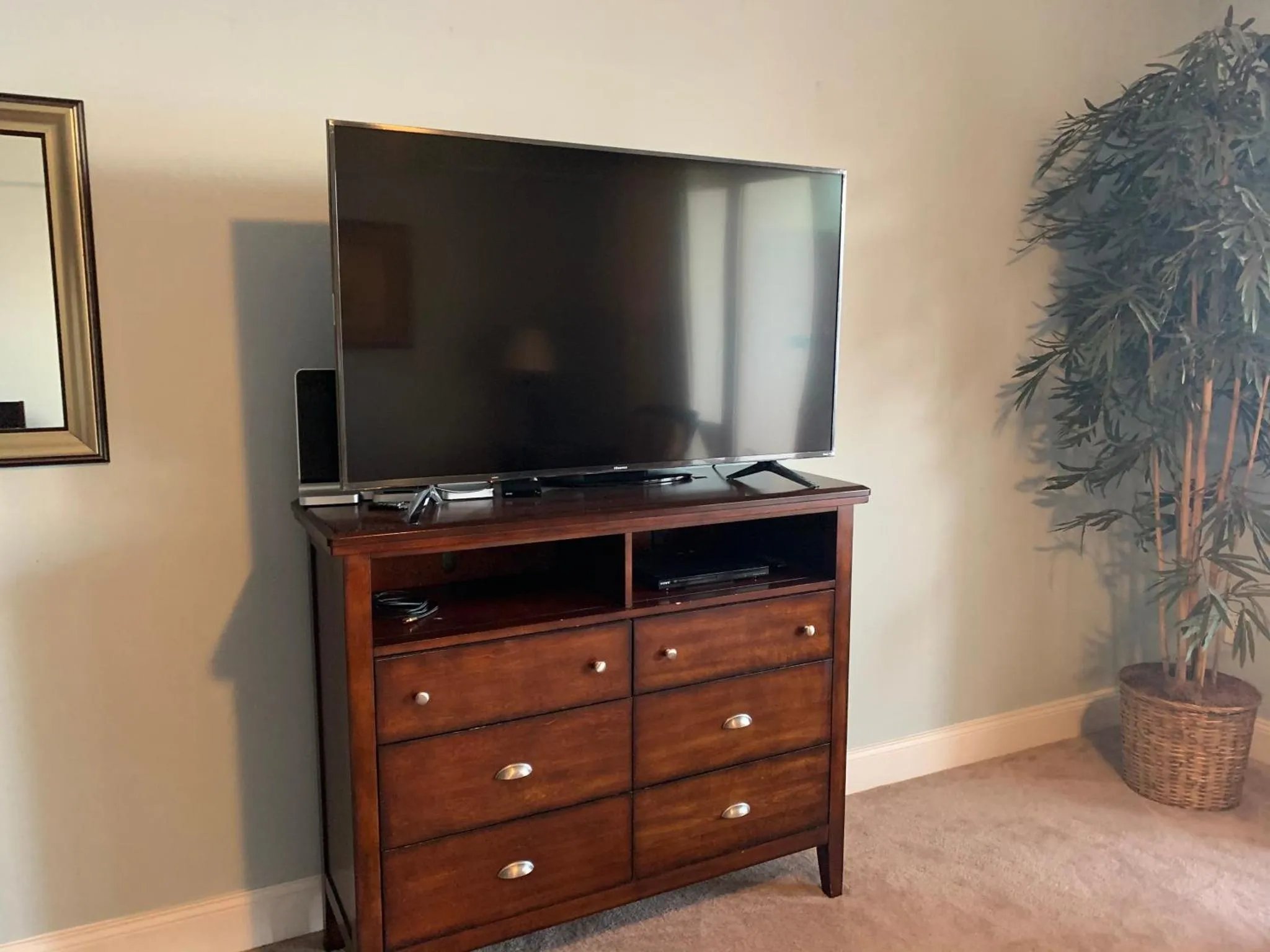Une télévision est posée sur une commode en bois sombre dans une pièce.