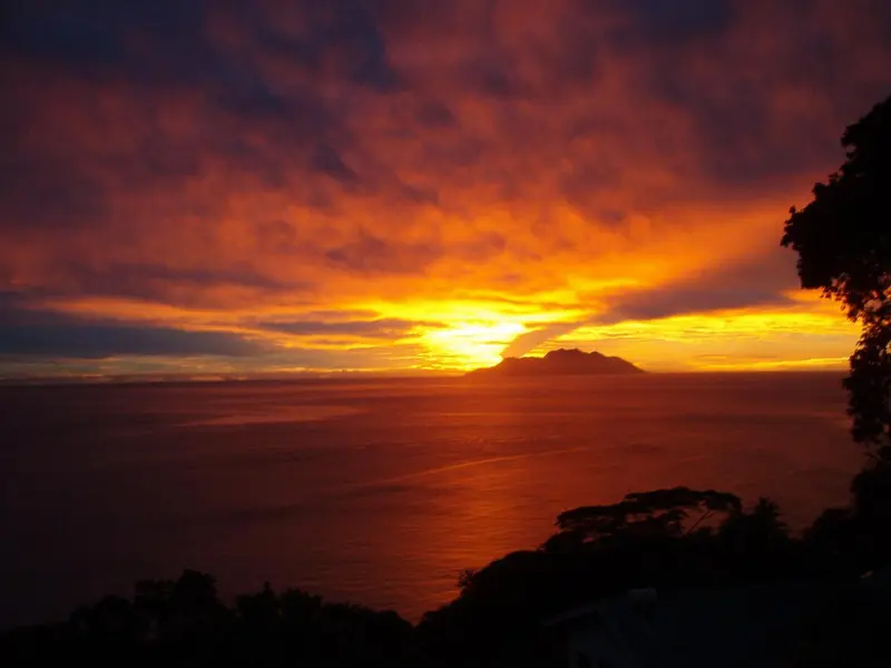 Coucher de soleil flamboyant sur l'océan et une île lointaine.