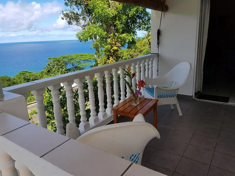 Terrasse carrelée avec mobilier blanc et vue sur la mer.