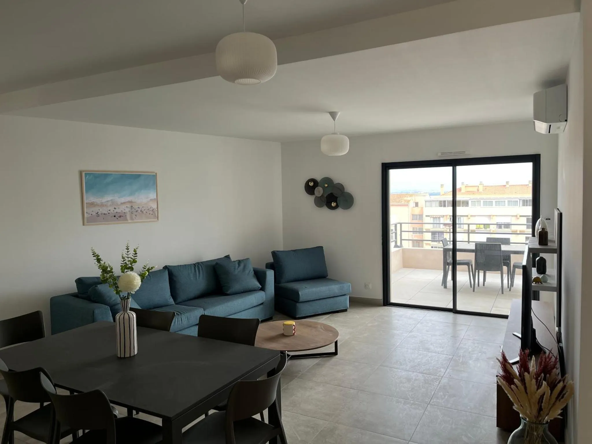 Un salon lumineux s'ouvre sur une terrasse avec table et chaises.