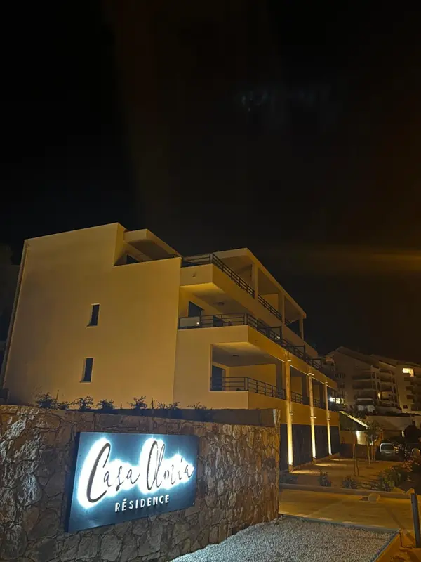 Façade d'un bâtiment blanc éclairé la nuit avec un panneau lumineux.