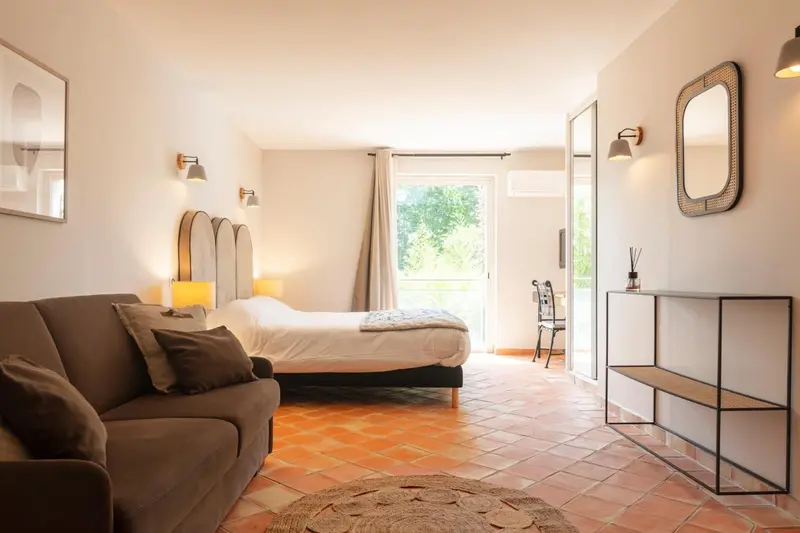 Une chambre lumineuse avec un canapé et un lit donnant sur une terrasse.