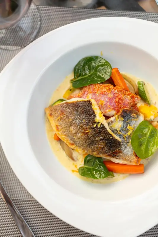 Un plat de poisson servi dans une assiette blanche.