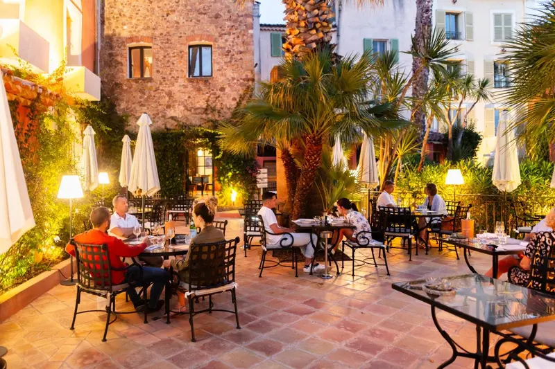 Une terrasse illuminée avec des tables et des chaises où des clients dînent.