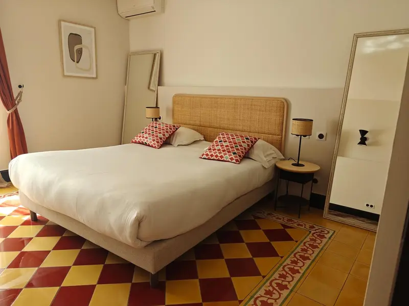 Une chambre lumineuse avec un grand lit et un sol carrelé.