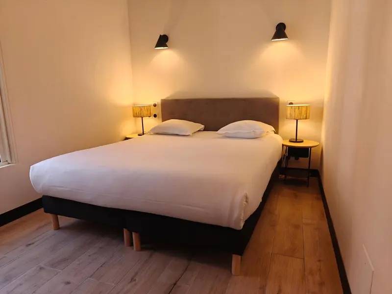 Une chambre lumineuse avec un grand lit et des lampes de chevet.