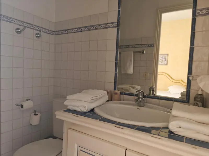 Une salle de bain claire avec lavabo, miroir et serviettes.