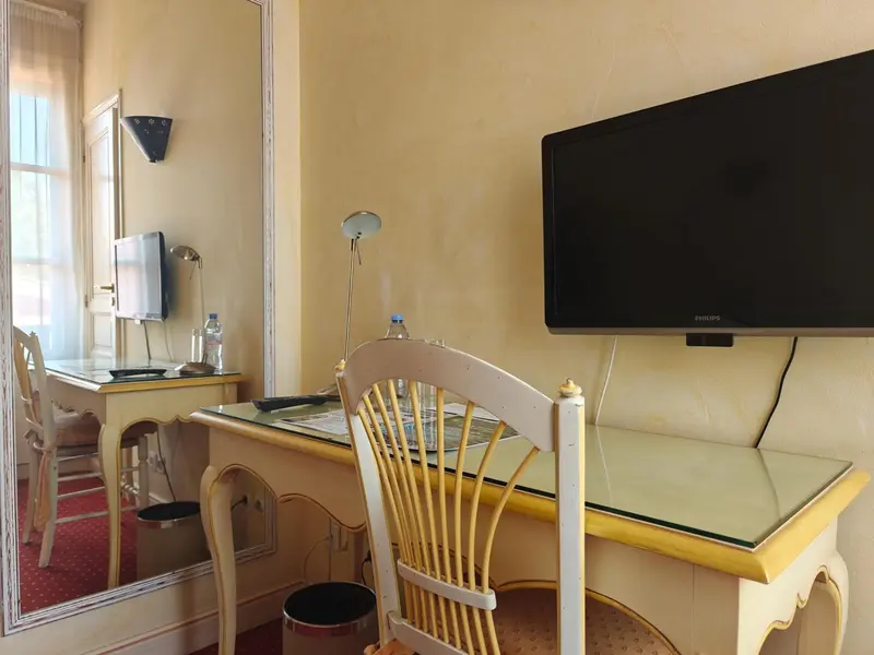 Une chambre lumineuse avec un bureau et une télévision murale.