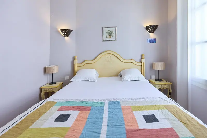 Une chambre lumineuse avec un lit double et des tables de chevet.