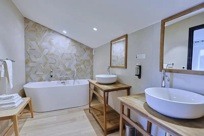 Une salle de bain moderne avec baignoire et deux vasques sur un meuble en bois.