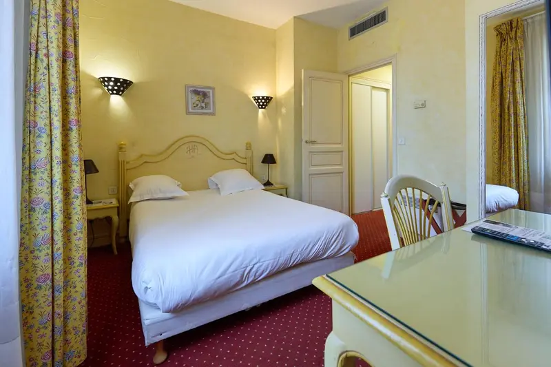 Chambre lumineuse avec un lit double et un bureau.