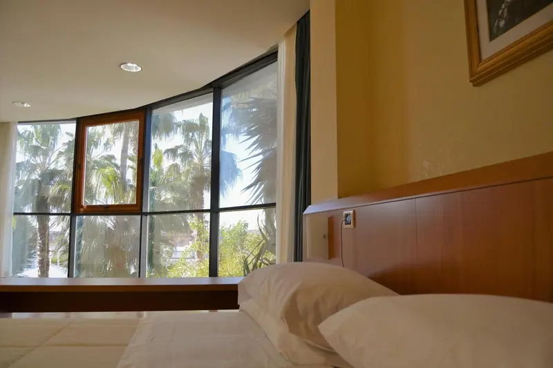 Une chambre lumineuse avec un grand lit et une vue sur la végétation tropicale.