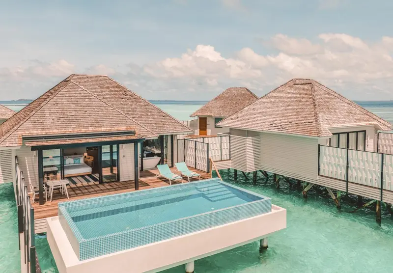 Plusieurs bungalows sur pilotis avec piscine privée et vue sur l'océan.