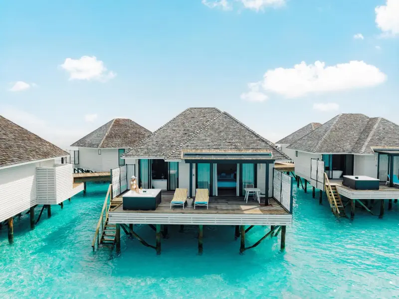 Maisons sur pilotis au-dessus d'une eau turquoise et claire.