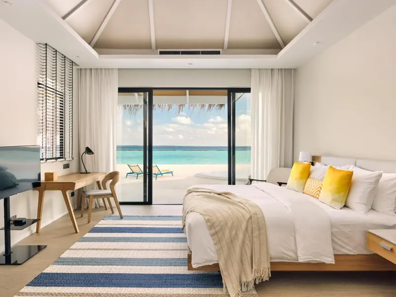 Une chambre lumineuse avec un grand lit donnant sur une plage.