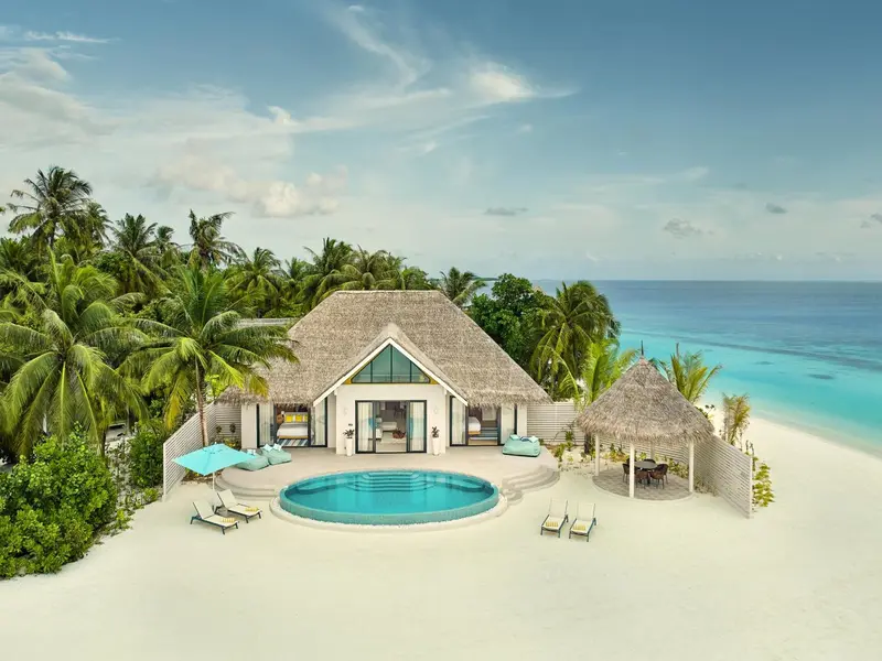 Villa avec piscine privée donnant sur une plage de sable blanc et la mer turquoise.