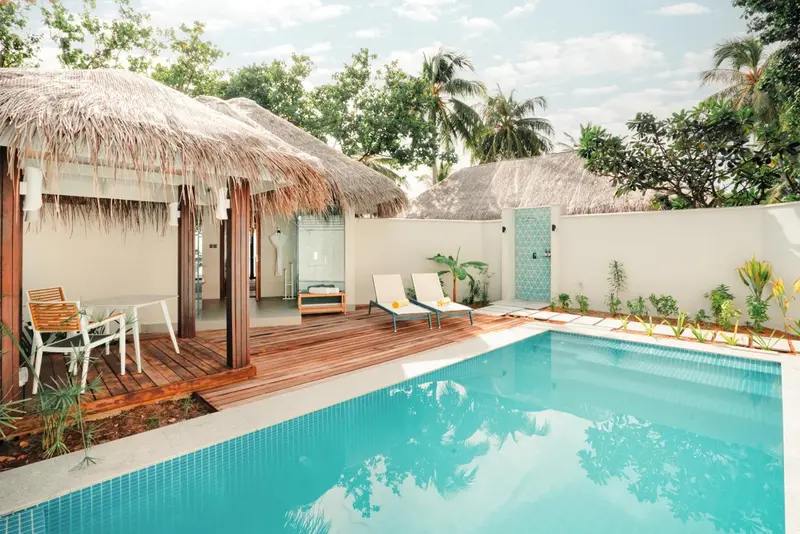 Terrasse en bois avec mobilier de jardin et piscine turquoise.