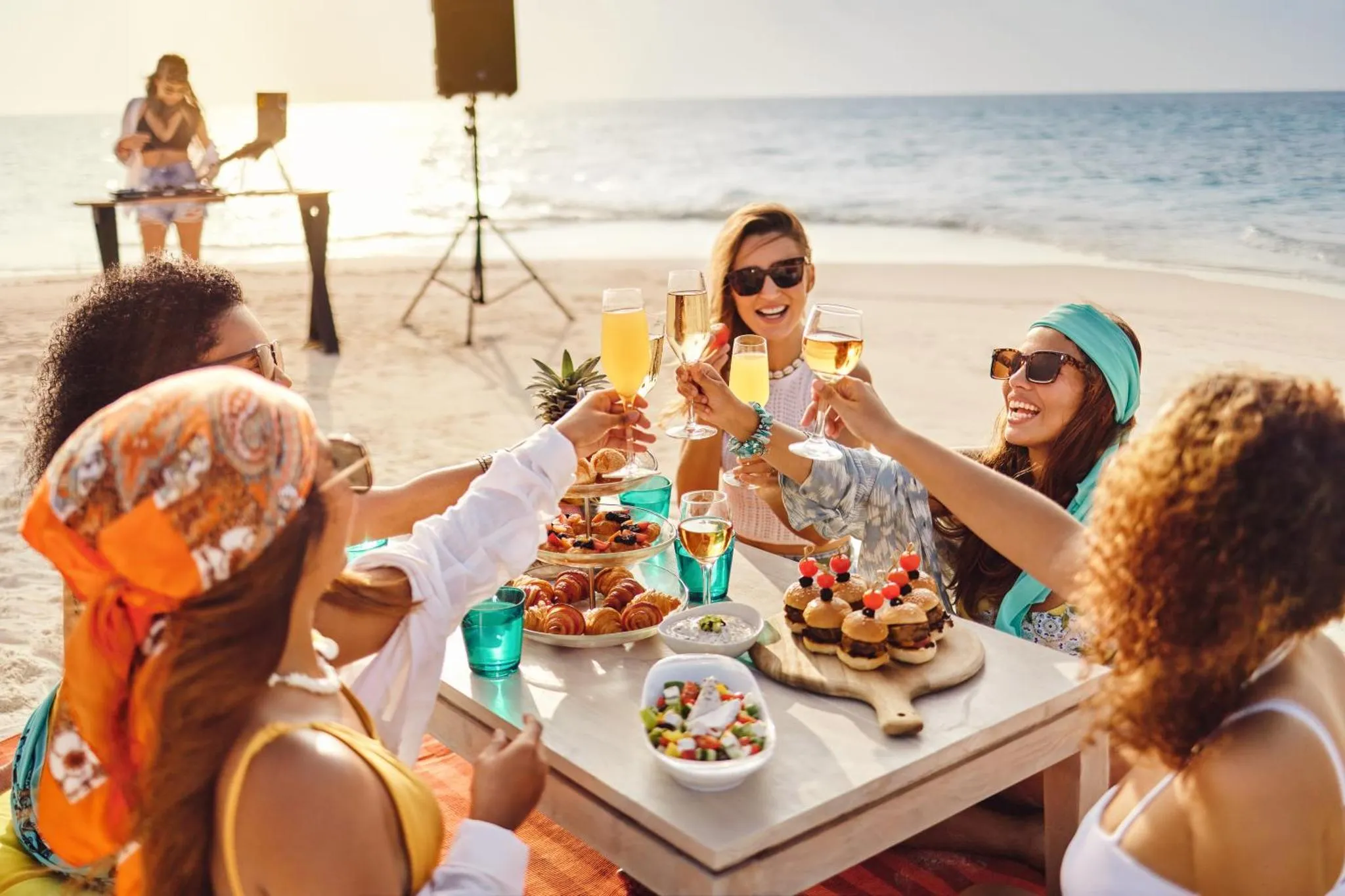 Un groupe de personnes trinque avec des verres sur une plage ensoleillée.