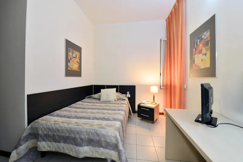 Une chambre lumineuse avec un lit simple et un bureau.