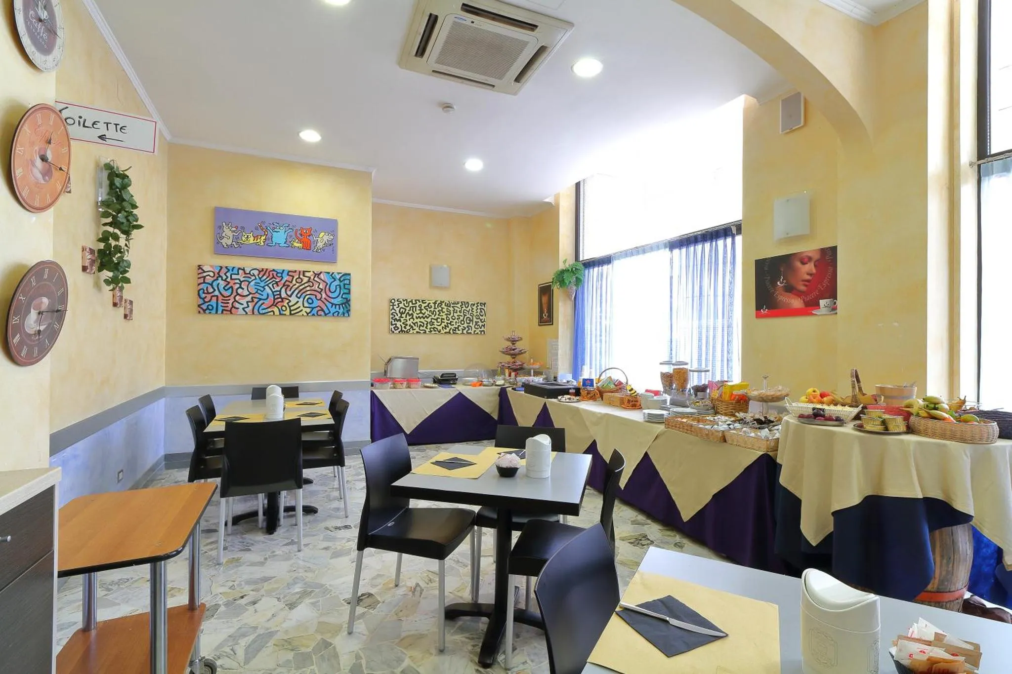 Une salle lumineuse avec des tables dressées pour le petit-déjeuner.