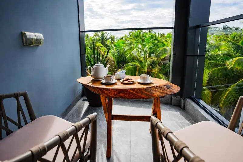 Une table ronde en bois avec une théière et des tasses sur un balcon.