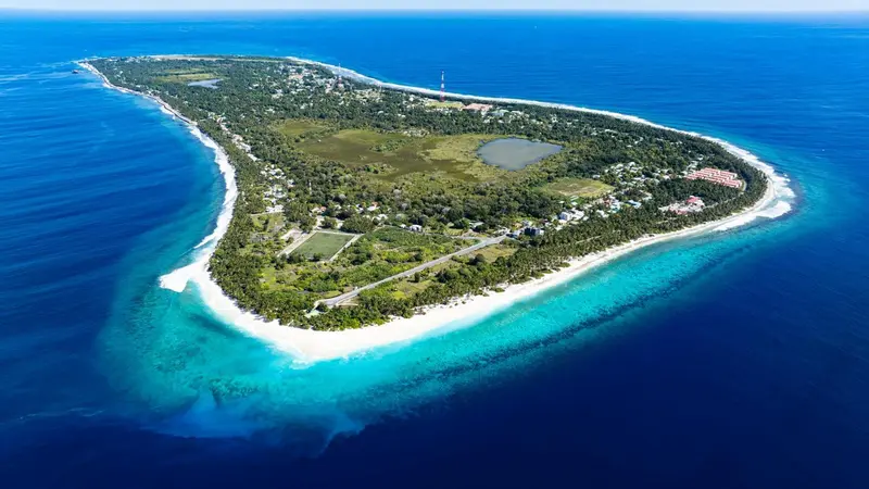 Vue aérienne d'une île tropicale bordée de plages et de végétation luxuriante.
