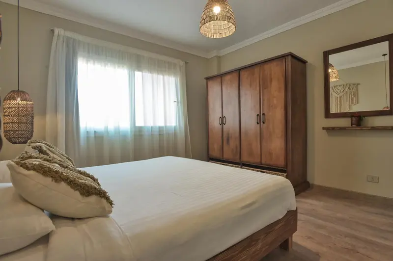 Une chambre lumineuse avec un grand lit et un placard en bois.