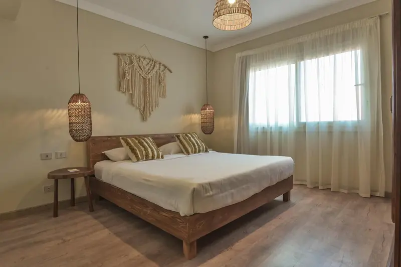 Une chambre lumineuse avec un grand lit recouvert de blanc.