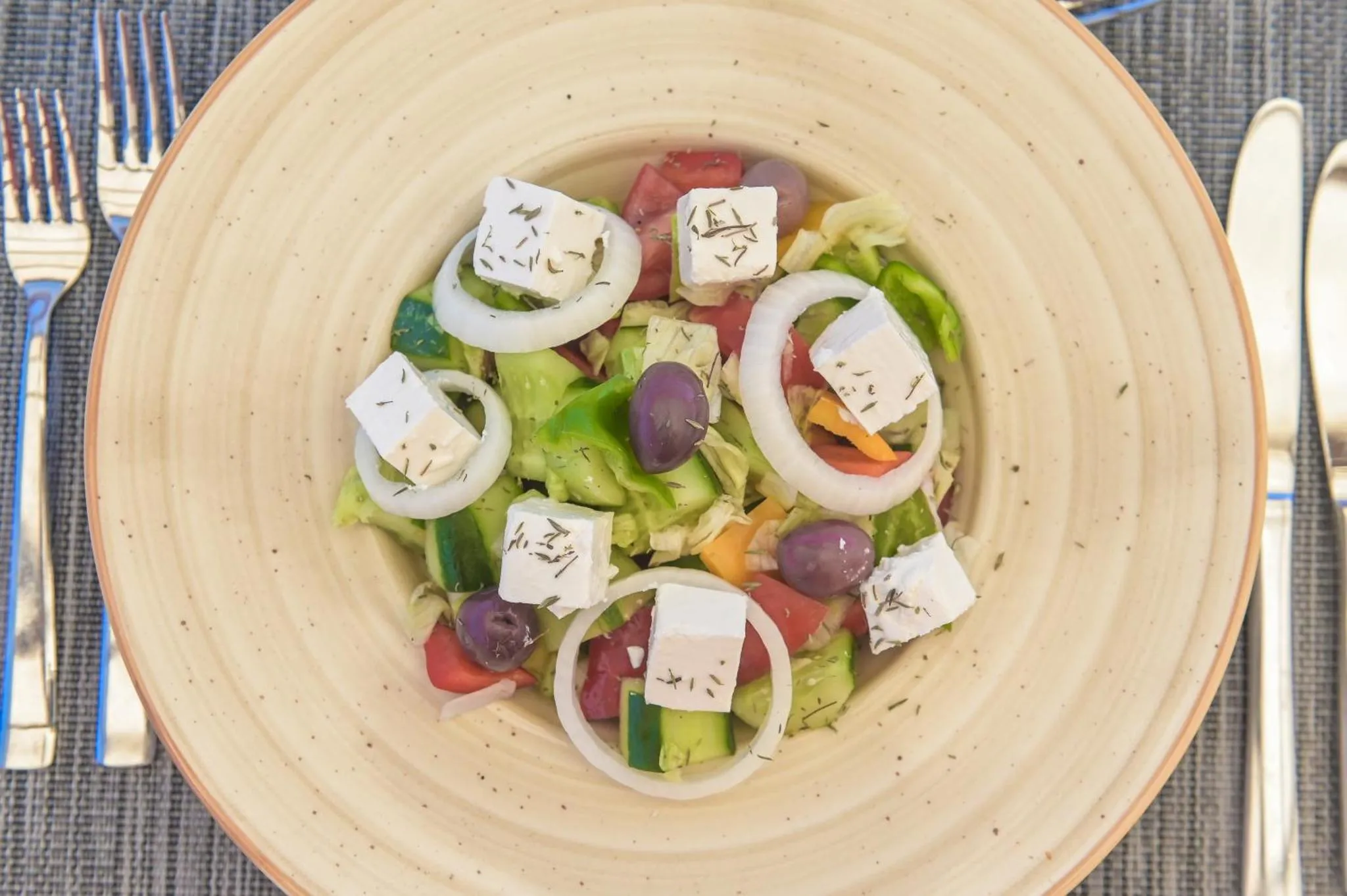 Une salade grecque colorée est présentée dans une assiette creuse.