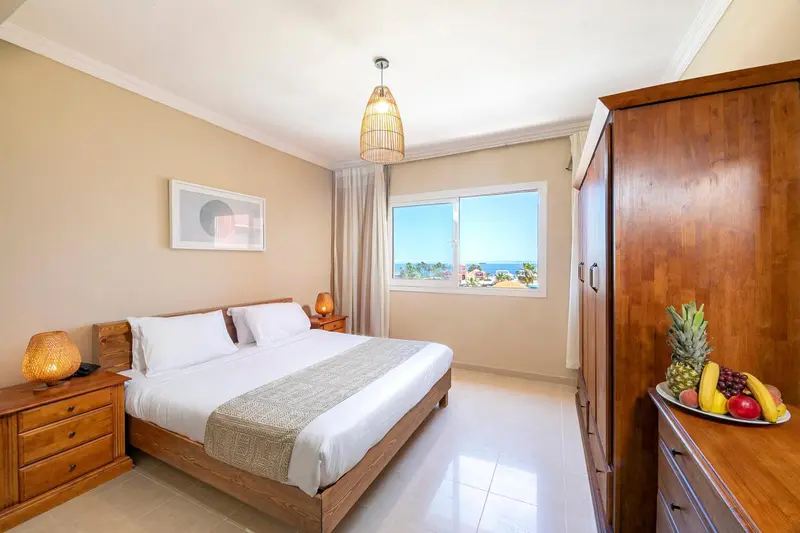 Chambre lumineuse avec un grand lit et une vue sur la mer.