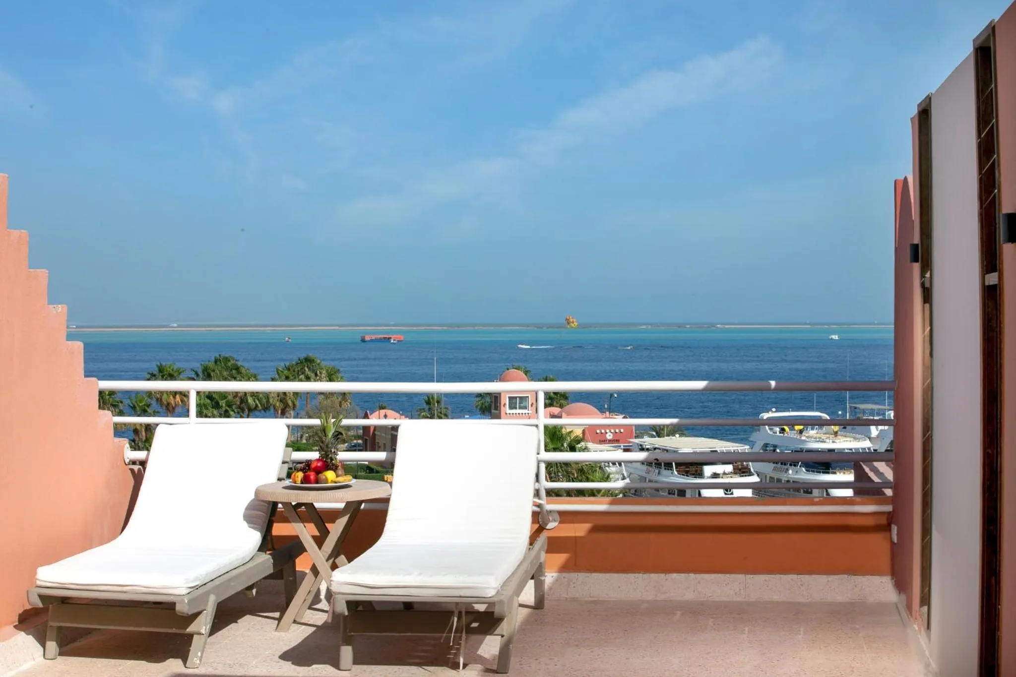 Deux transats blancs invitent à la détente sur une terrasse ensoleillée avec vue sur la mer.