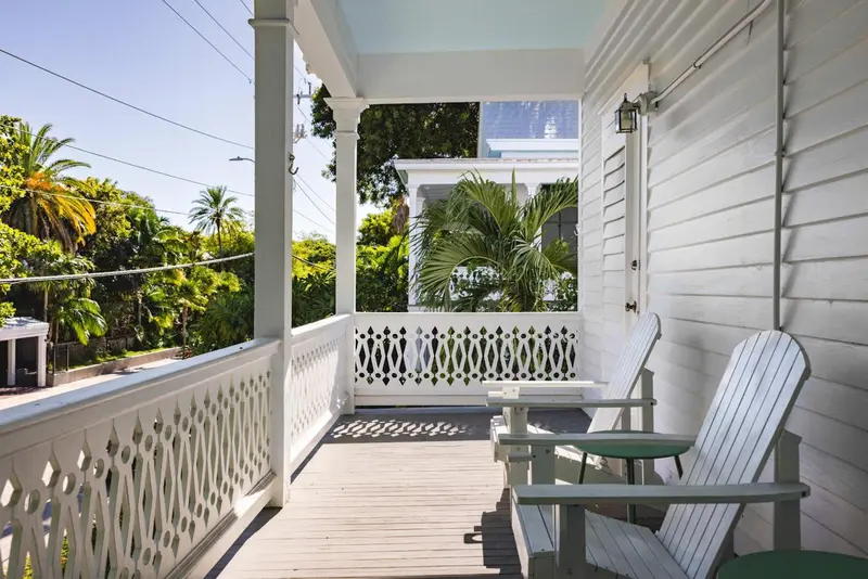 Terrasse en bois blanc avec mobilier d'extérieur et végétation luxuriante.