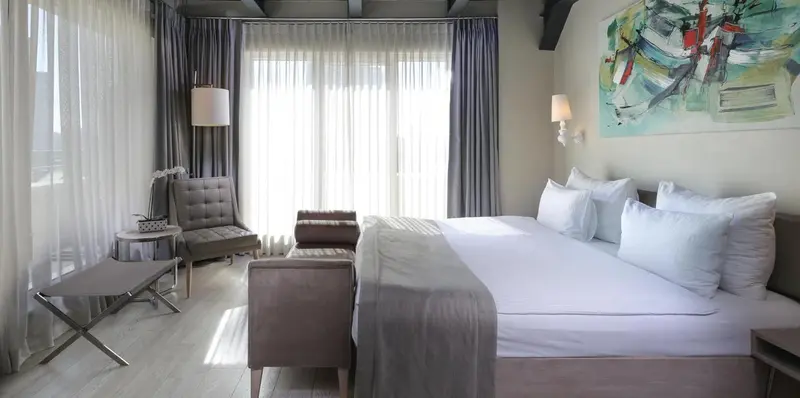 Une chambre lumineuse avec un grand lit et un coin salon.