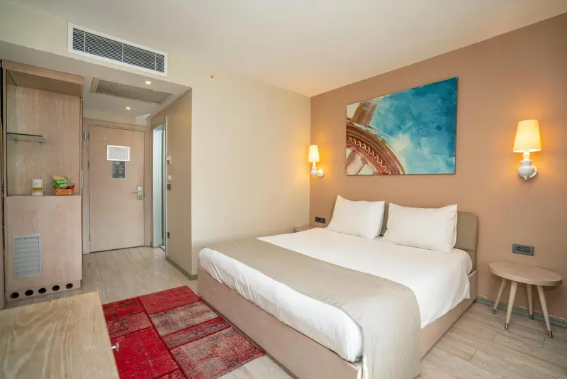 Une chambre lumineuse avec un grand lit et un tableau abstrait au mur.