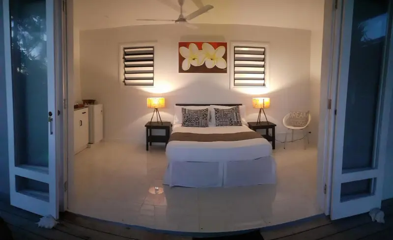 Une chambre lumineuse avec un lit double et des fenêtres ouvertes.