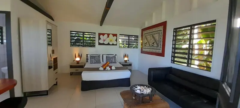 Une chambre lumineuse avec un lit fait et un coin salon.