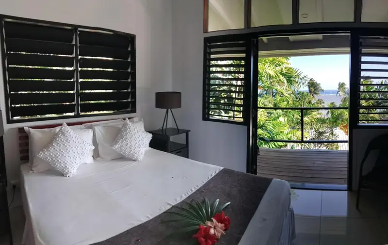 Une chambre lumineuse avec un grand lit et une vue sur la végétation.