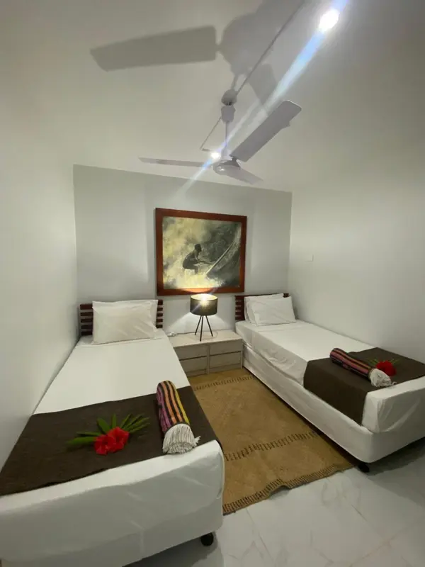 Une chambre lumineuse avec deux lits simples et une décoration murale.